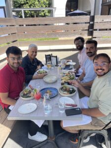 5 people eating lunch during a sunny day.